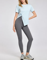 Woman wearing a light blue top and gray leggings on a white background