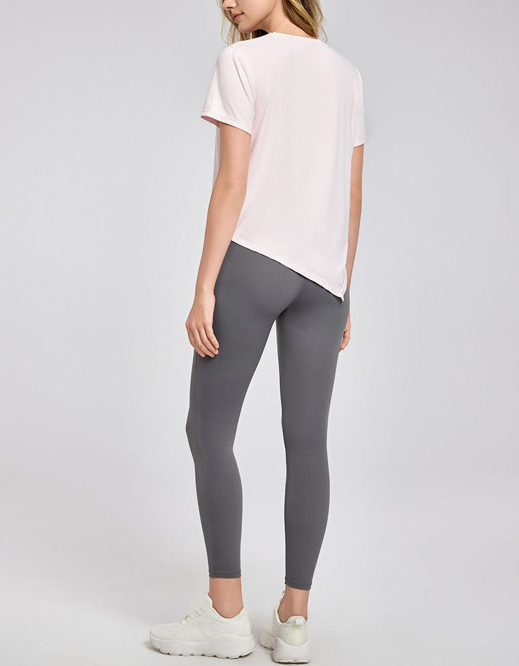 Person wearing a white t-shirt and gray leggings on a plain background