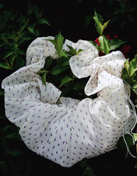 Close‑up of ruched scrunchie handle and ruffled fabric on cream shoulder bag with purple dots