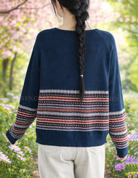 Back view of person wearing a navy sweater with a colorful pattern in a garden setting