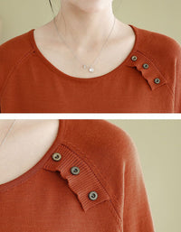 Close-up of a orange sweater with button details on a beige background
