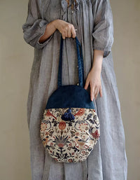 Person holding a floral-patterned handbag against a plain background