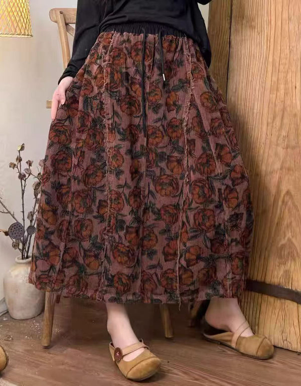 Person wearing a patterned skirt standing in a room with wooden floor and wall.