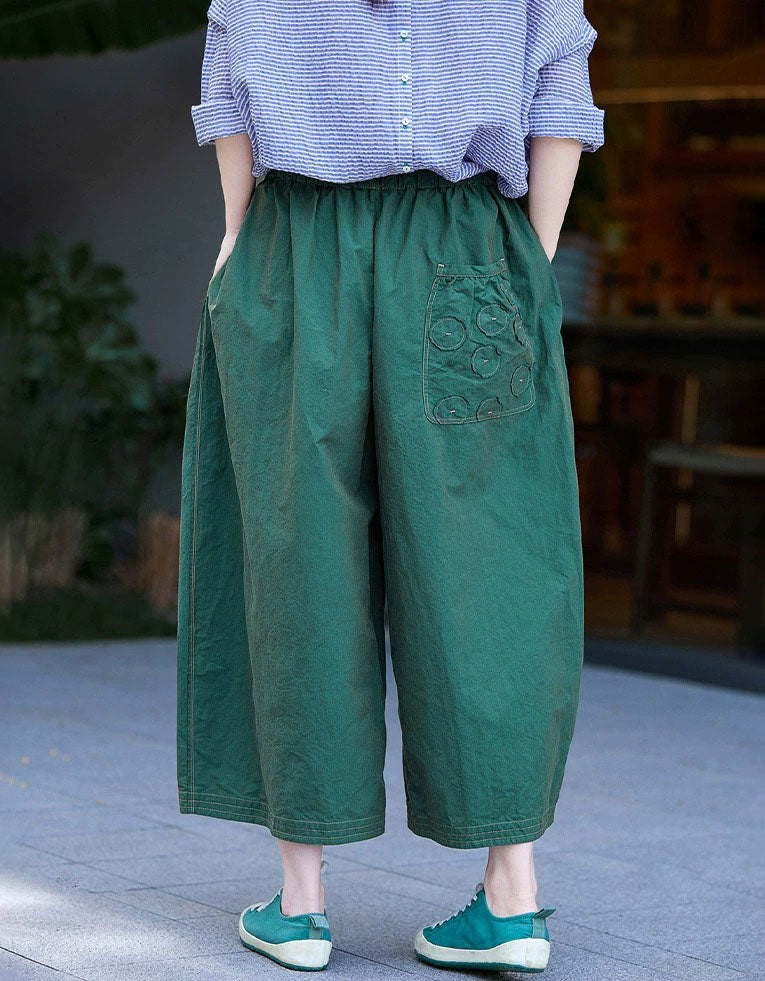 Person wearing green wide-leg pants with a decorative pocket in an outdoor setting back view
