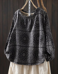 Black patterned shirt with white pants against a dark wooden background