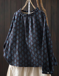 Dark patterned blouse with long sleeves on a wooden hanger against a dark wooden background