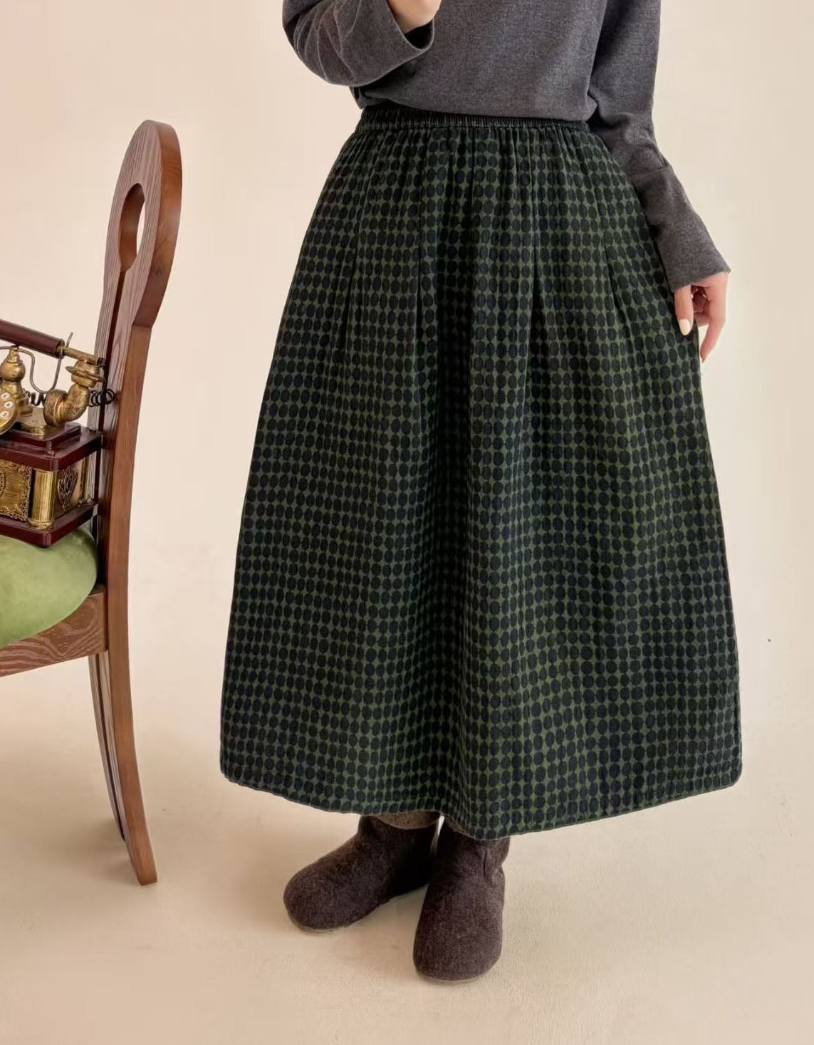 Woman wearing green polka dot midi skirt with gray top and brown felt boots