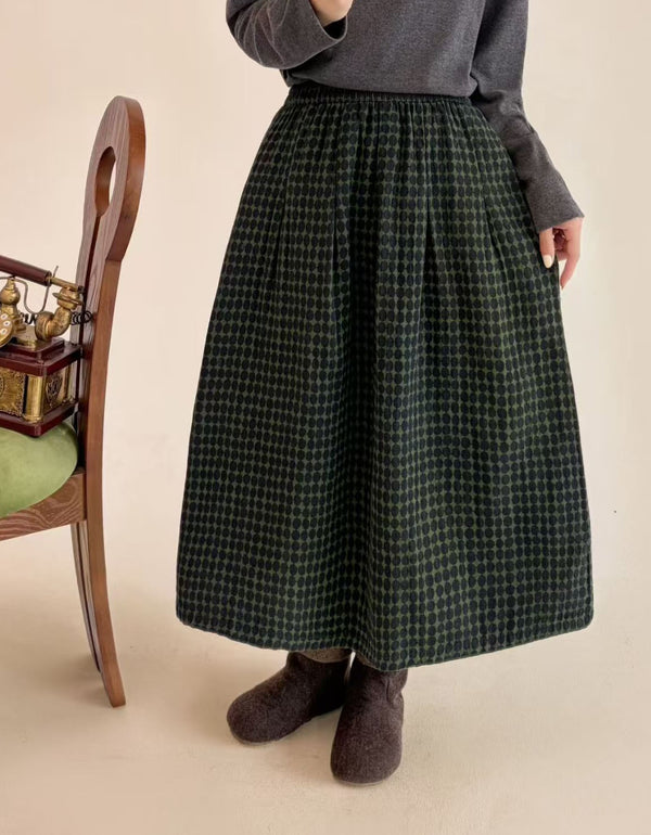 Woman wearing green polka dot midi skirt with gray top and brown felt boots