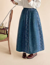 Woman wearing blue floral midi skirt with gray top and brown felt boots