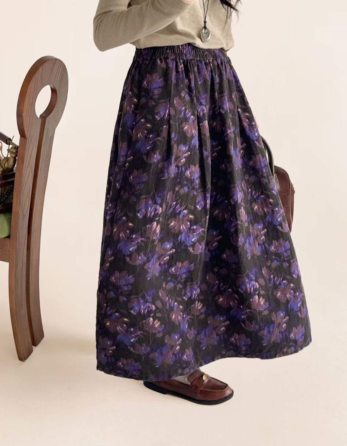 Woman wearing purple floral midi skirt with gray top and brown felt boots