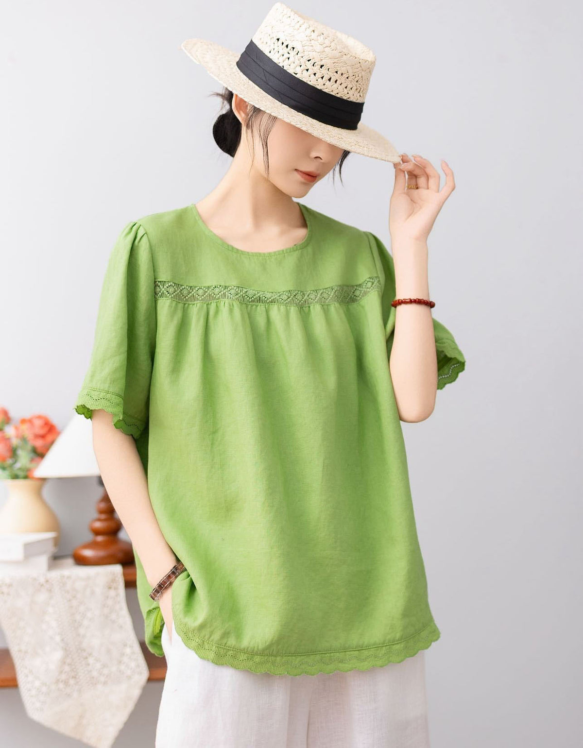 Person wearing a green top and straw hat on a plain background