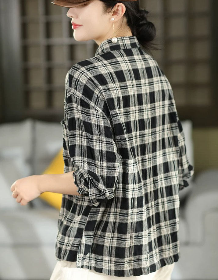 A woman wearing a black and white plaid long-sleeve shirt, shown from a side-back angle in an indoor setting.