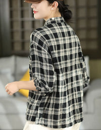 A woman wearing a black and white plaid long-sleeve shirt, shown from a side-back angle in an indoor setting.