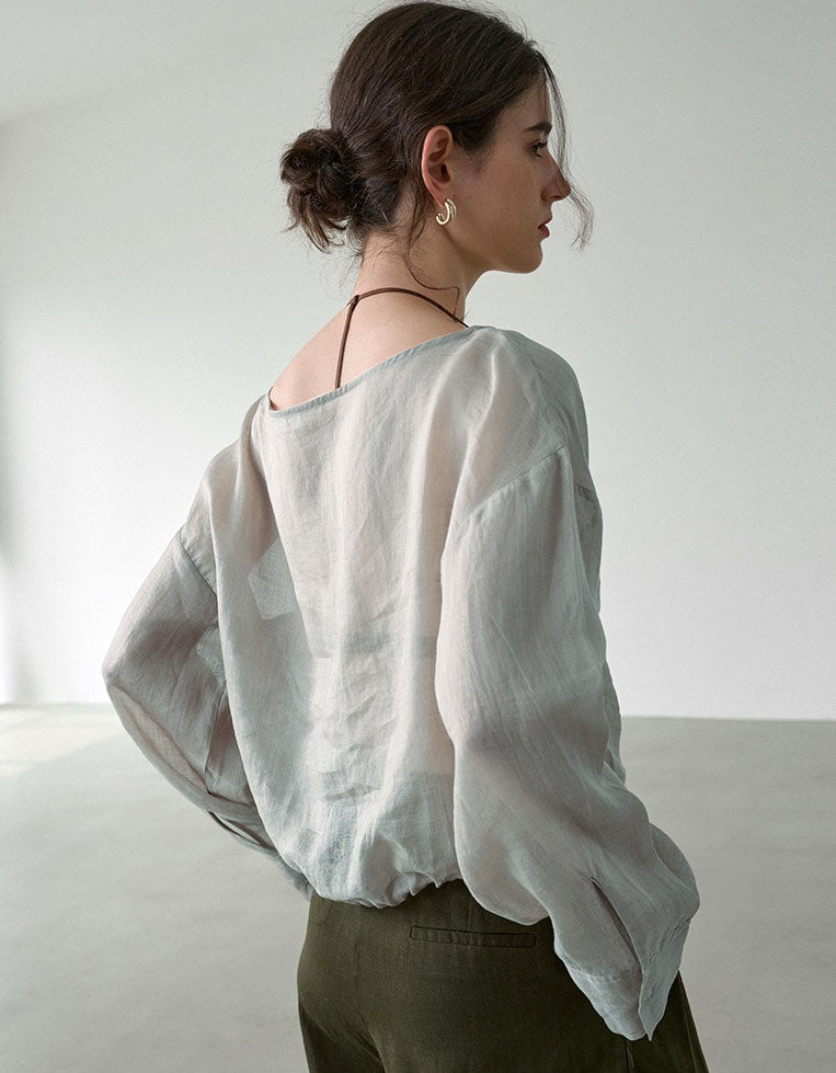 Woman wearing a light-colored blouse against a plain background