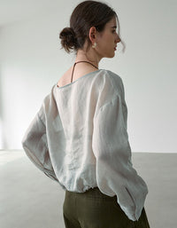 Woman wearing a light-colored blouse against a plain background