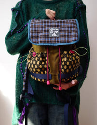 Side angle of cute tartan mini backpack showing padded shoulder straps and drawstring closure