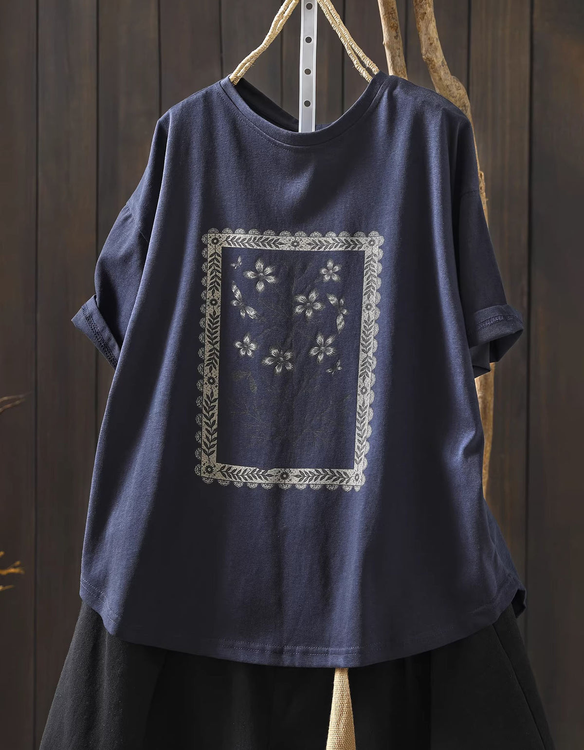 Navy blue t-shirt with white floral embroidery on a wooden background
