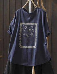 Navy blue t-shirt with white floral embroidery on a wooden background