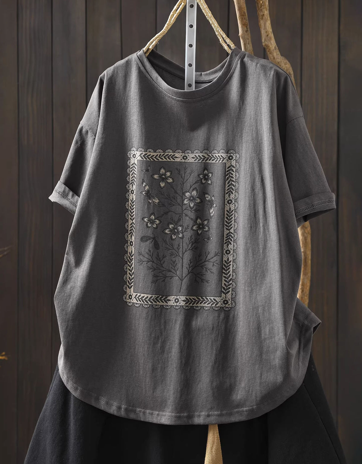 Gray t-shirt with floral embroidery on a wooden background