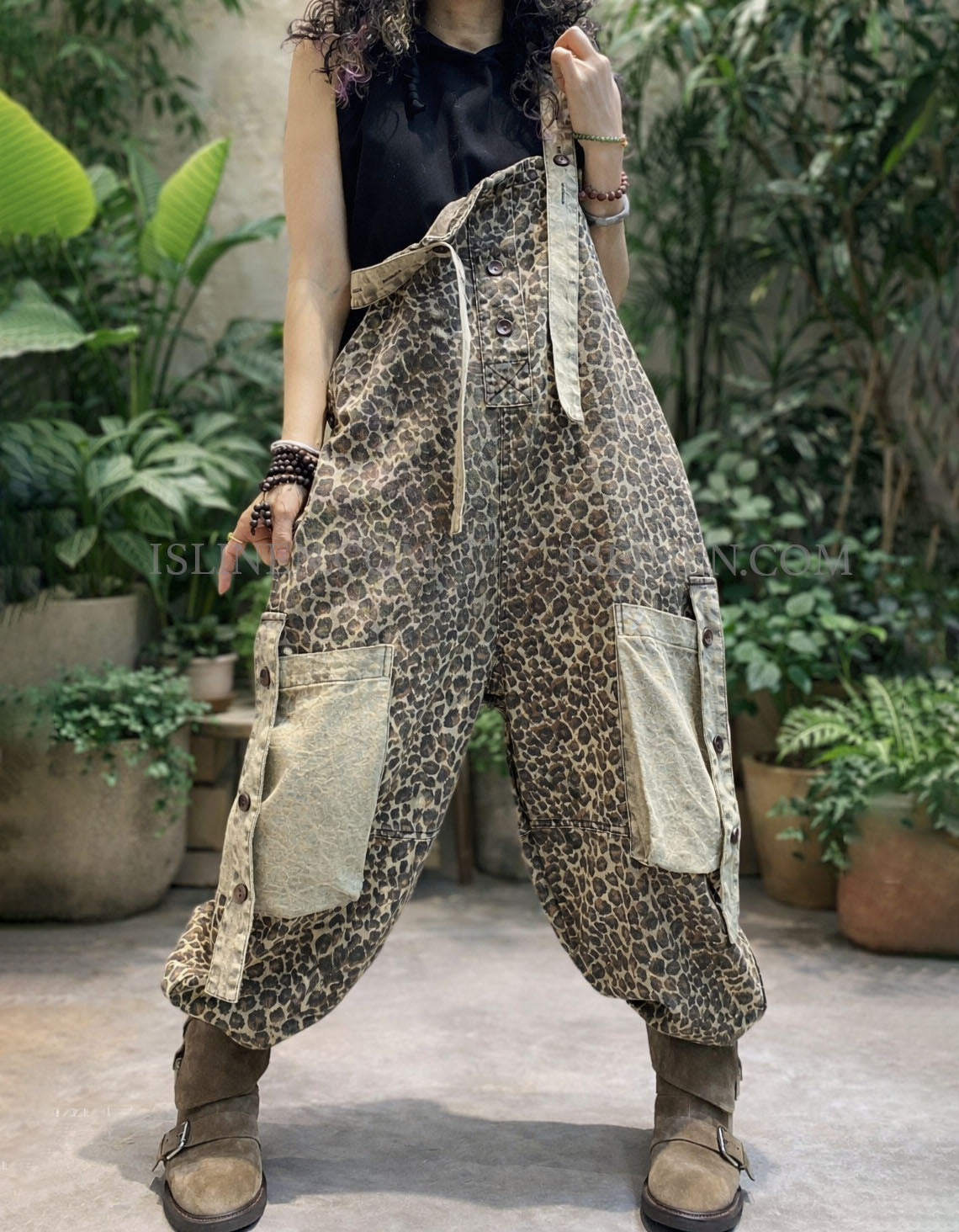 Person wearing leopard print patchwork pants in an outdoor setting with plants.