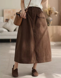 Person wearing a brown skirt and holding a brown bag in a neutral setting
