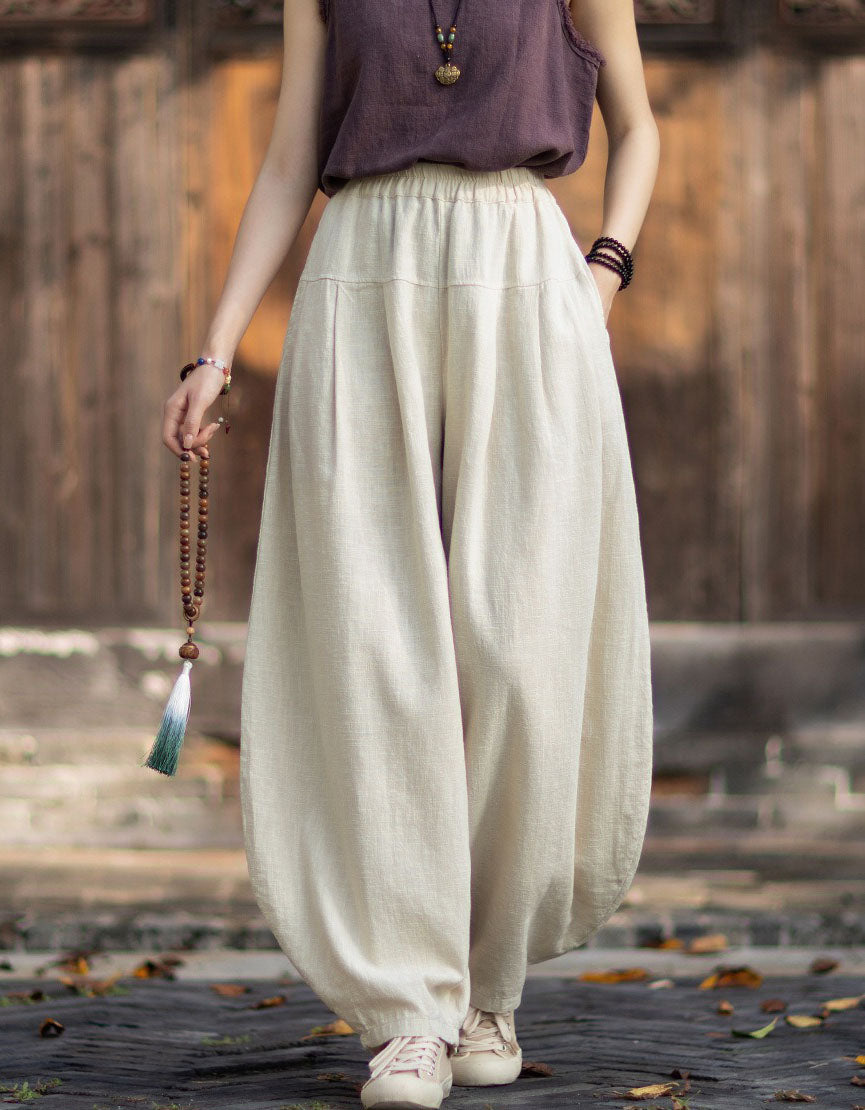 Woman walking outdoors wearing forest green linen harem pants styled with boho accessories.