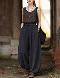 Linen harem pants with high elastic waist and lantern legs, worn with brown top and sneakers outdoors.