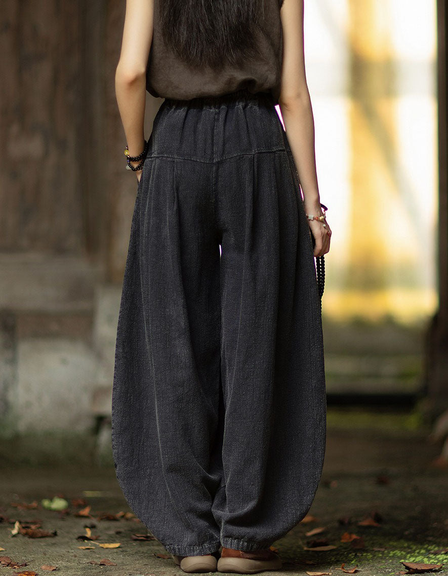 Back view of black linen harem pants with gathered waistband and loose draped legs.