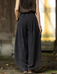 Back view of black linen harem pants with gathered waistband and loose draped legs.
