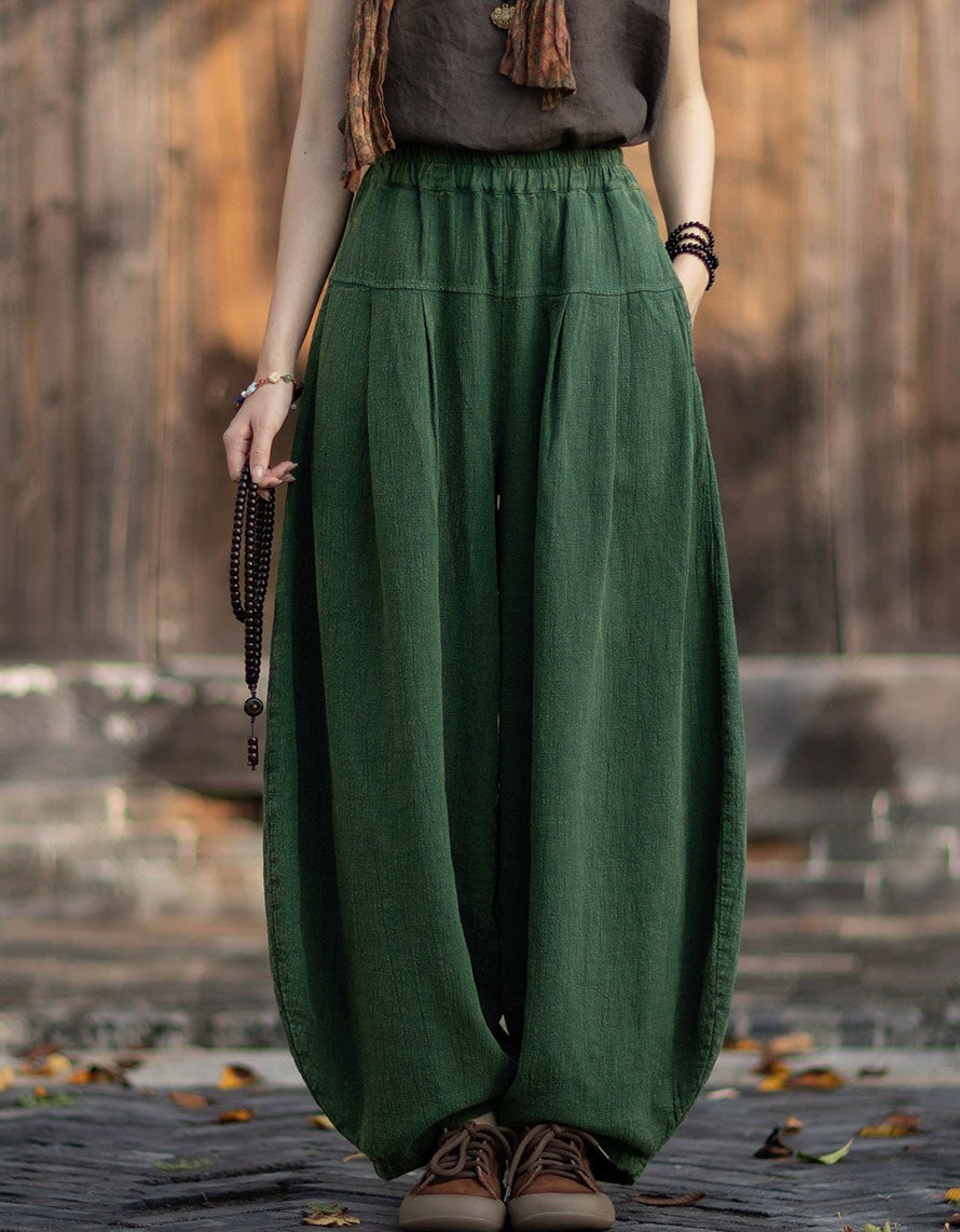 Deep green linen lantern pants showing wide leg shape and relaxed high waist.