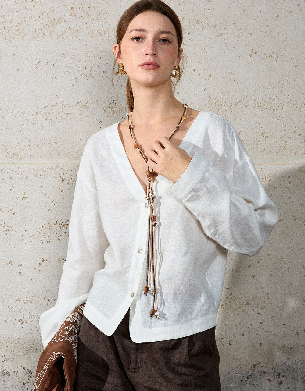 Woman wearing a white blouse with a textured wall background