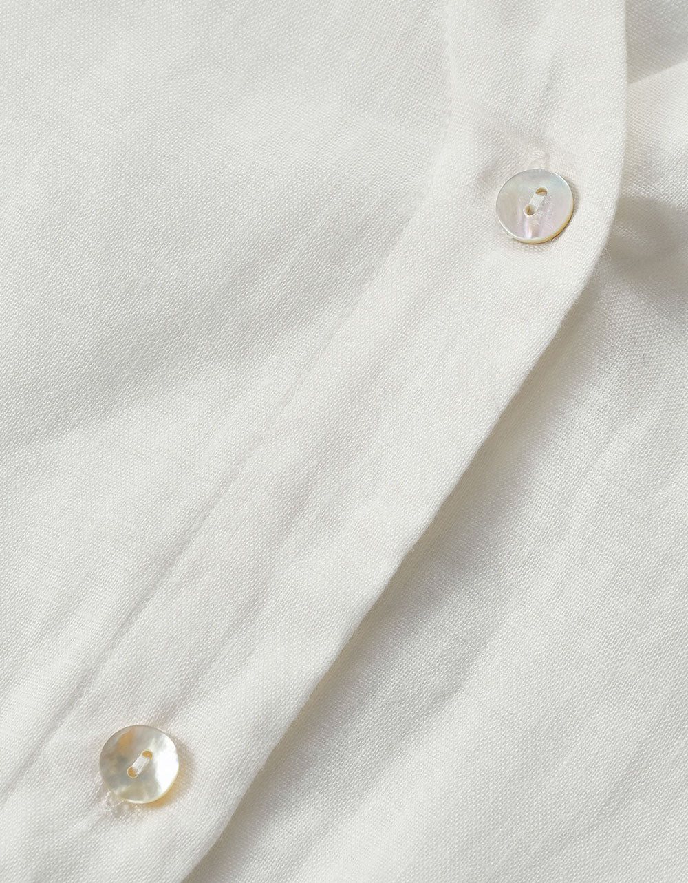 Close-up of a white shirt with buttons on a light gray background