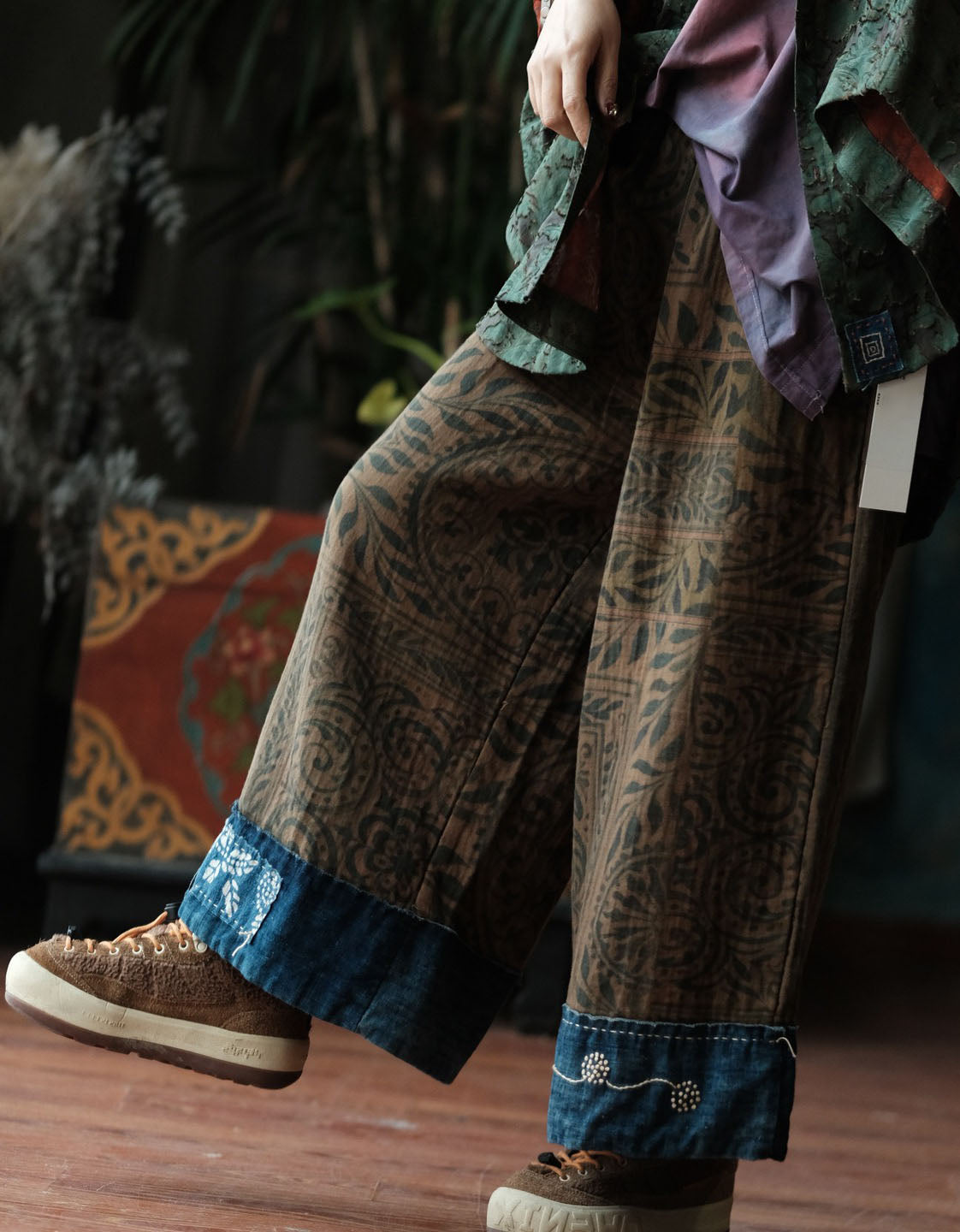 Woman wearing boho printed wide leg palazzo pants with brown ethnic pattern and dark blue contrast hem indoors