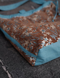 Floral drawstring tote bag with blue shoulder straps and vintage print