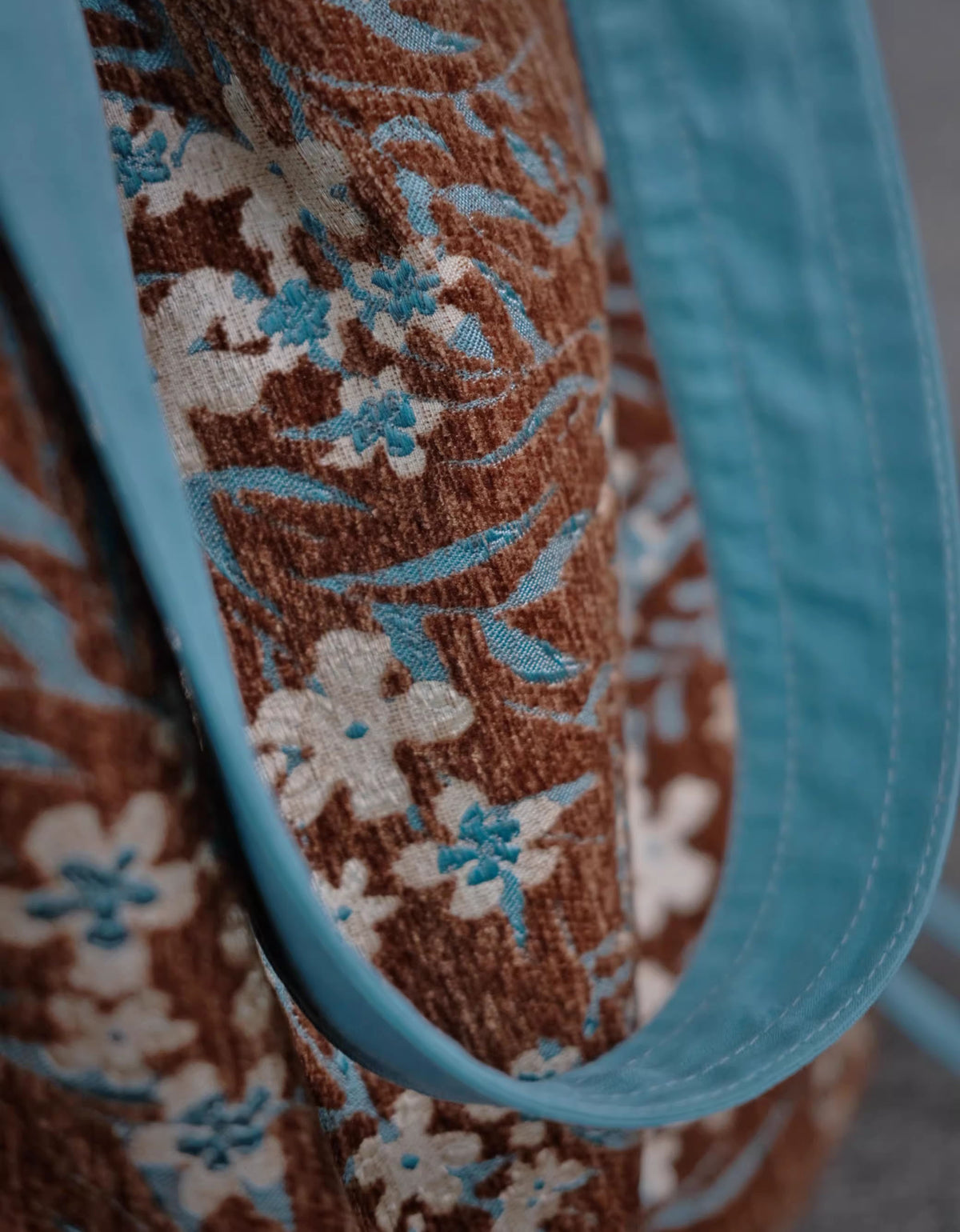 Close up of floral canvas shoulder bag with brown and blue botanical design