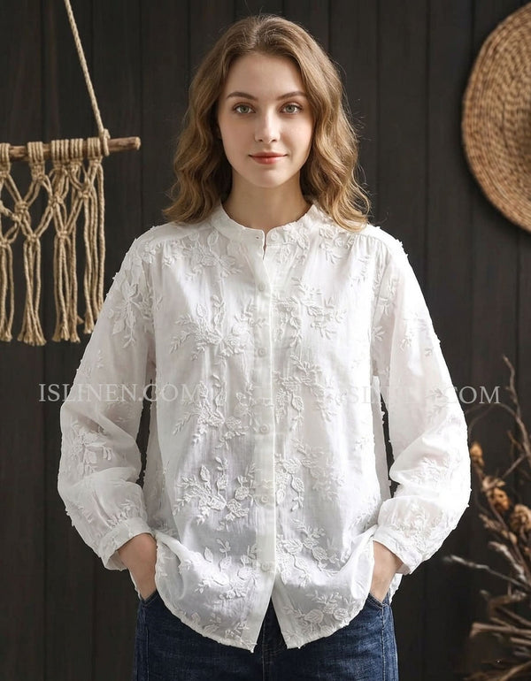 White embroidered blouse with floral lace details and button front hanging on rack