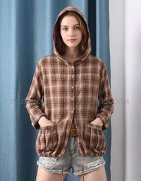 Person wearing a brown plaid hoodie with a blue curtain background
