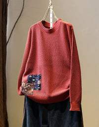 Women’s red long sleeve knit pullover styled with dark denim jeans