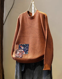 Women’s orange long sleeve knit pullover styled with dark denim jeans