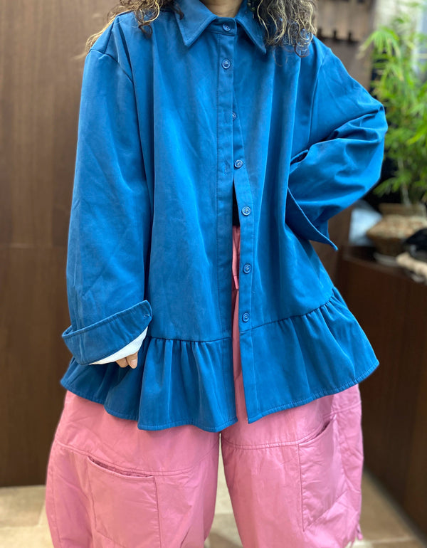 Pointed collar and button-front design of a women's oversized blue shirt.