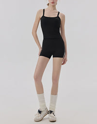Person wearing a black leotard, shorts, and white socks on a plain background