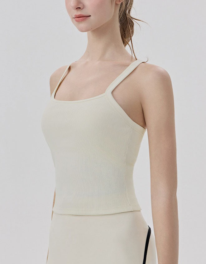 Woman wearing a beige tank top against a plain background