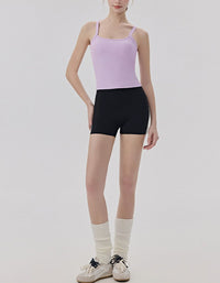 Person wearing a light purple tank top and black shorts with white socks on a plain background