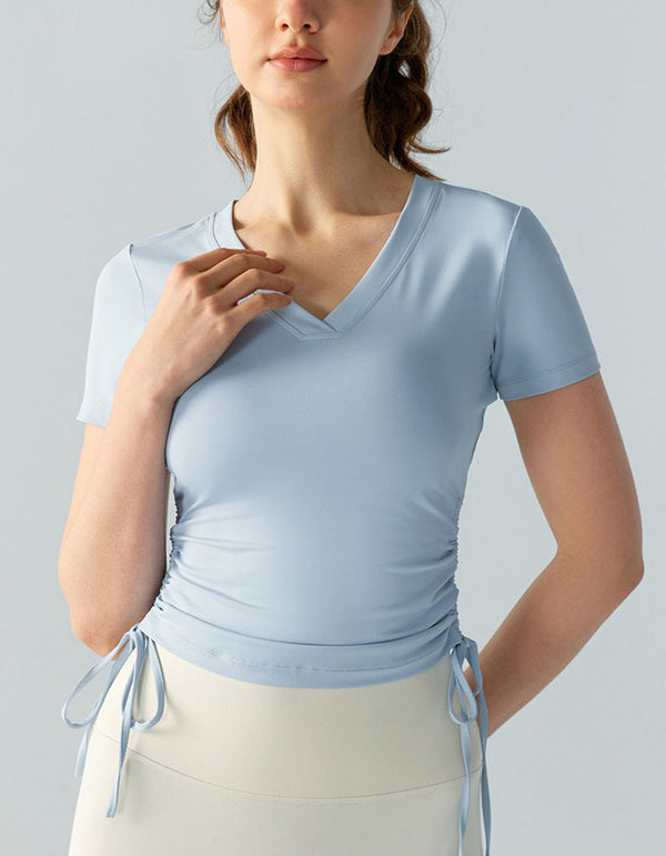 Woman wearing a light blue top with tied sleeves against a gray background