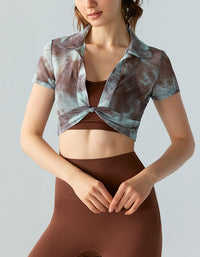 Woman wearing a patterned crop top and brown leggings on a plain background