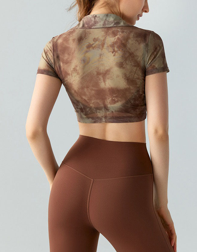 Person wearing a camouflage crop top and brown leggings on a light gray background back view