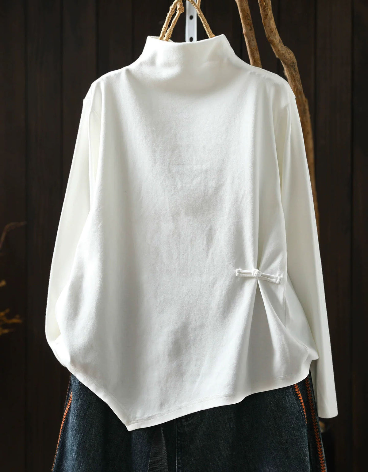 White women's high neck sweater with asymmetrical hem and side button detail