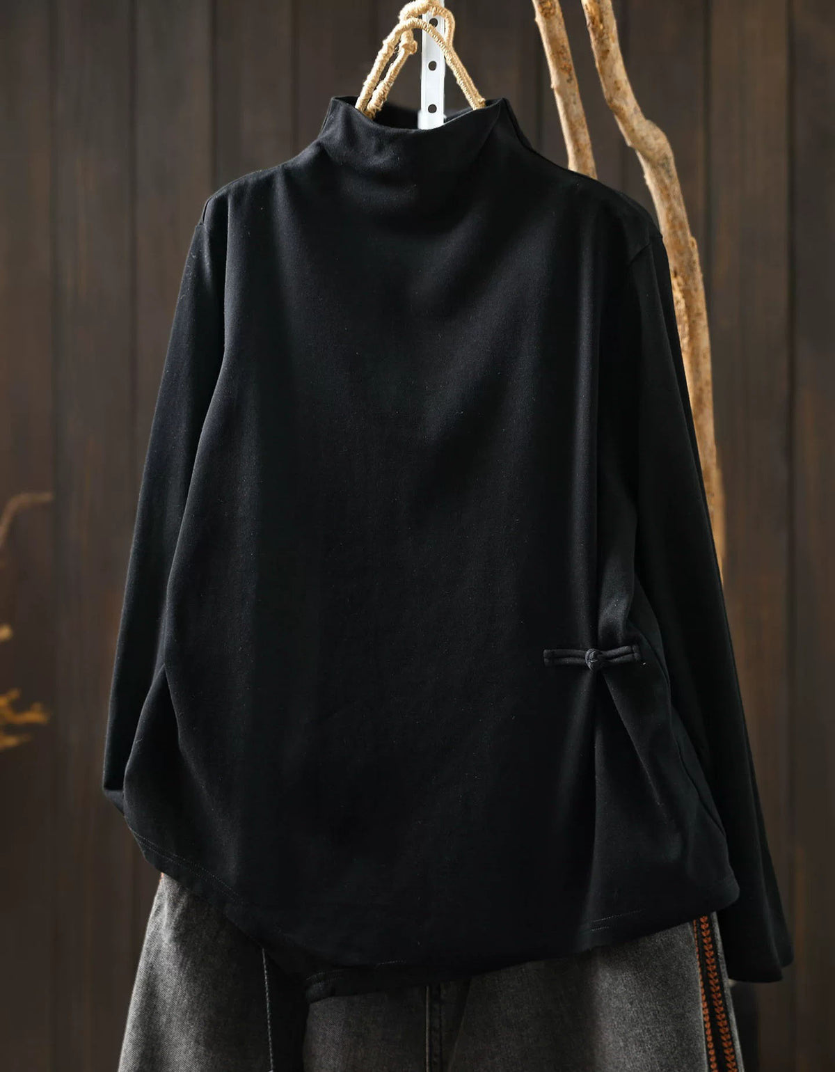 Black women's high neck sweater with asymmetrical hem and side button detail