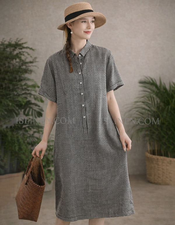 Woman wearing a checkered dress with a straw hat and holding a bag indoors.