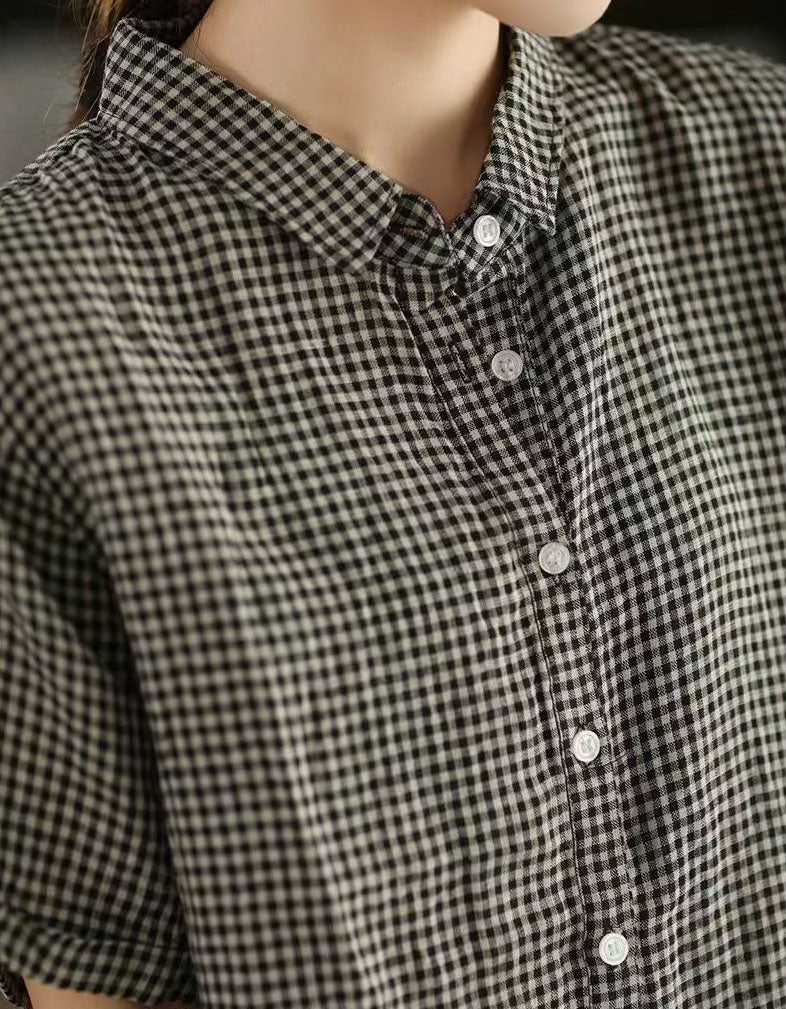 Close-up of a person wearing a black and white checkered shirt with buttons.